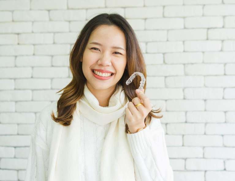 Woman holding Invisalign Clear Aligners
