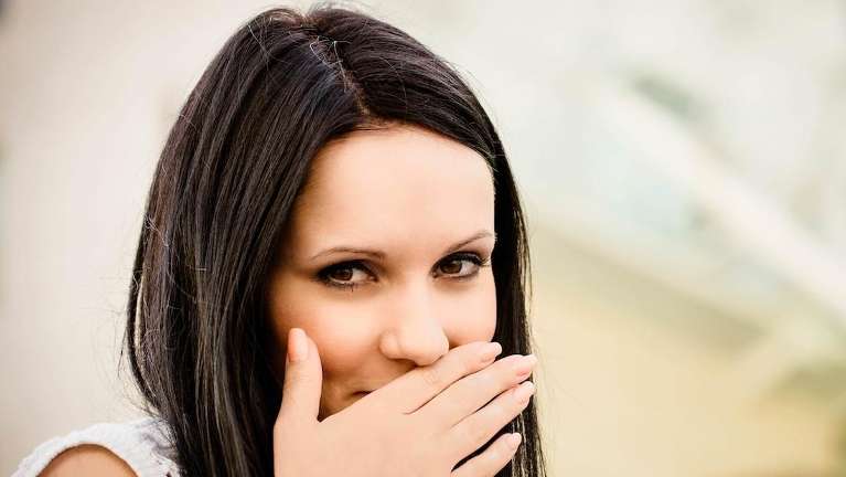 woman putting face over mouth | dentist who accept lending club